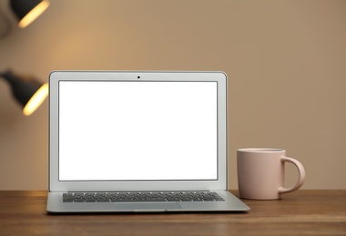 Photo of Laptop with blank screen on table indoors. Space for text