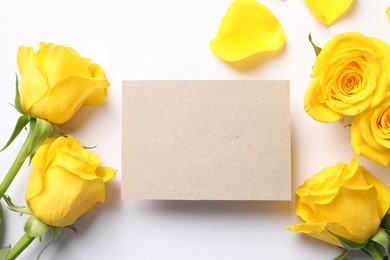 Photo of Beautiful yellow roses and blank card on white background, flat lay. Space for text