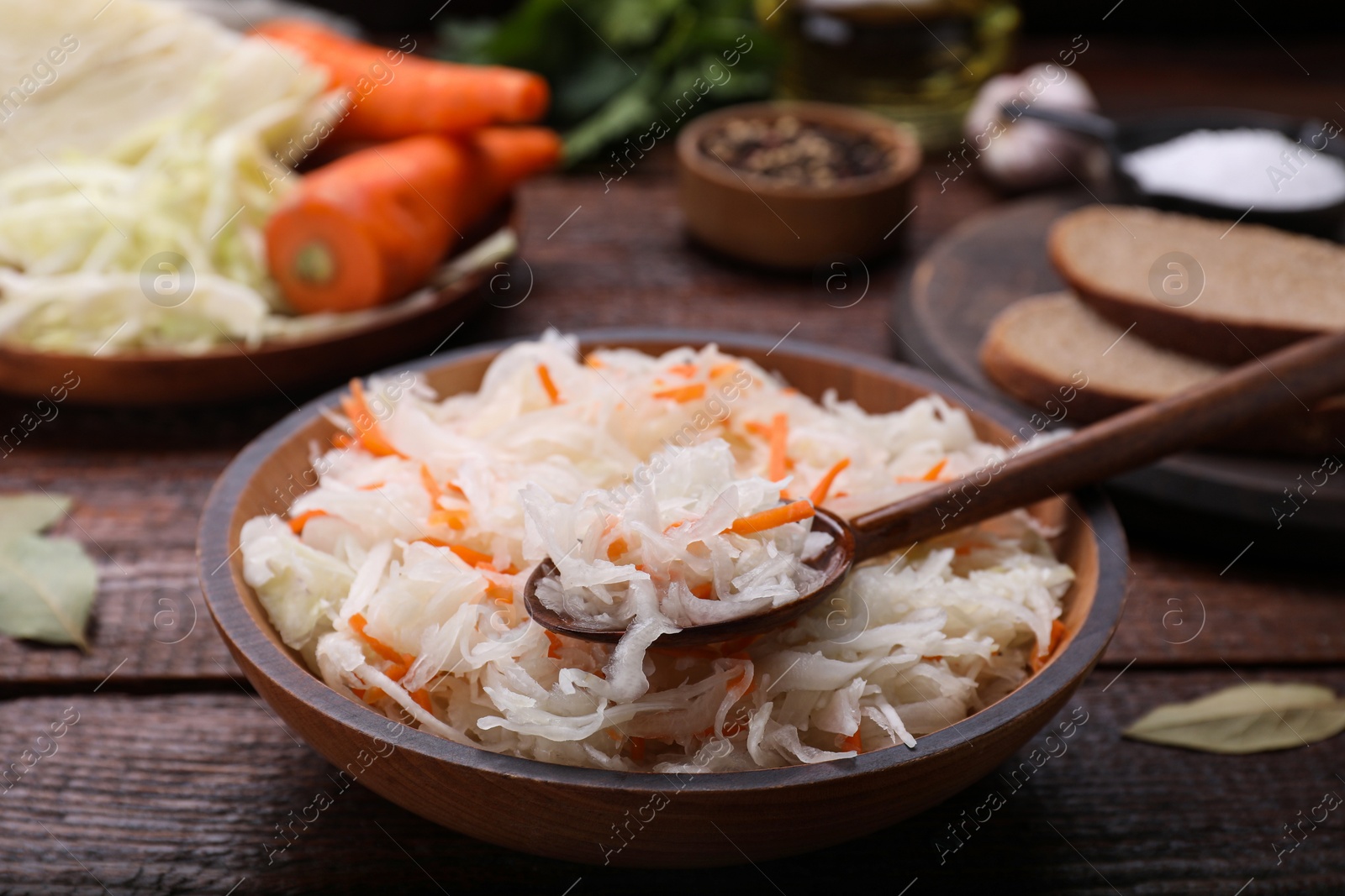 Photo of Bowl of tasty sauerkraut on wooden table, closeup