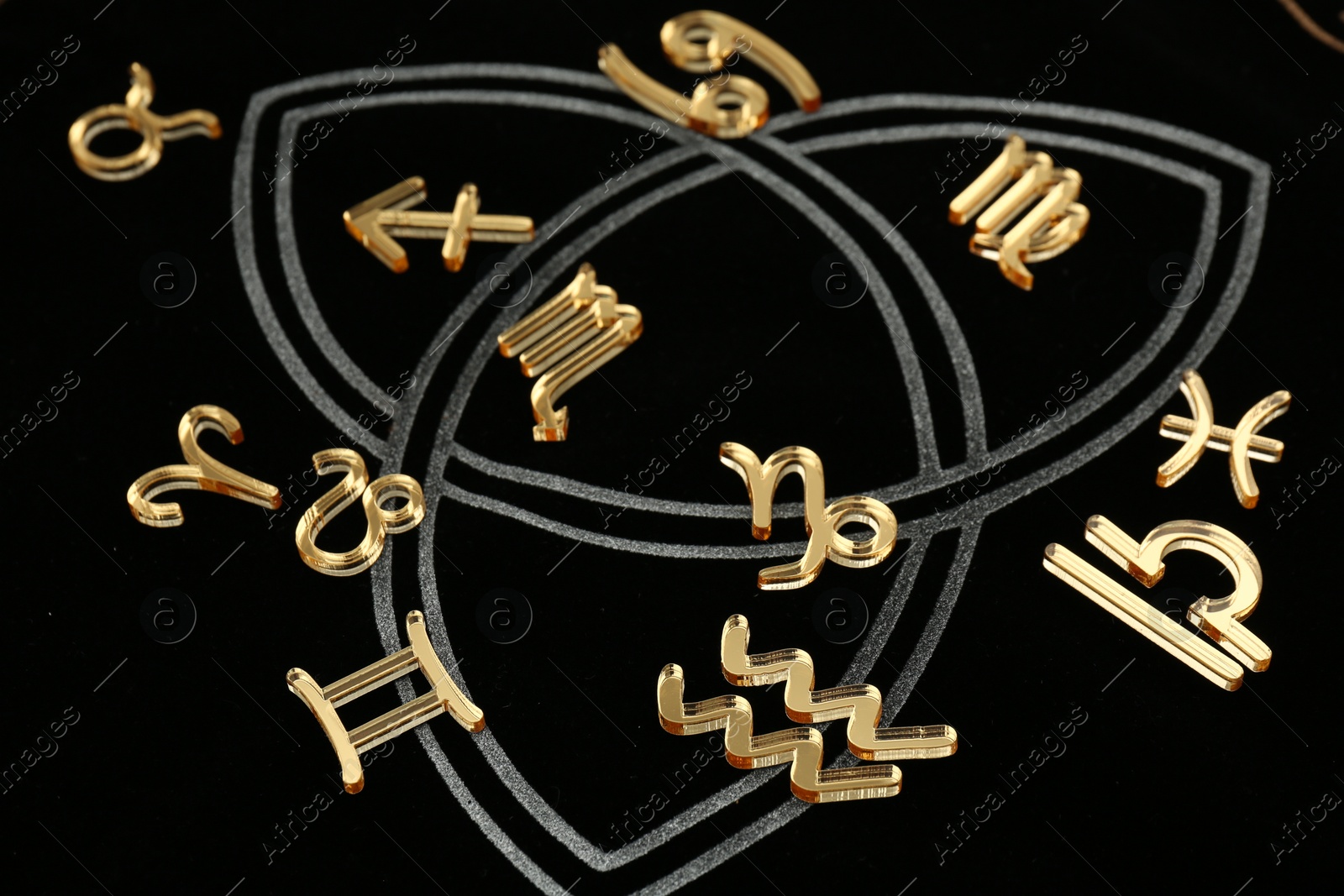 Photo of Golden zodiac signs on dark background, closeup