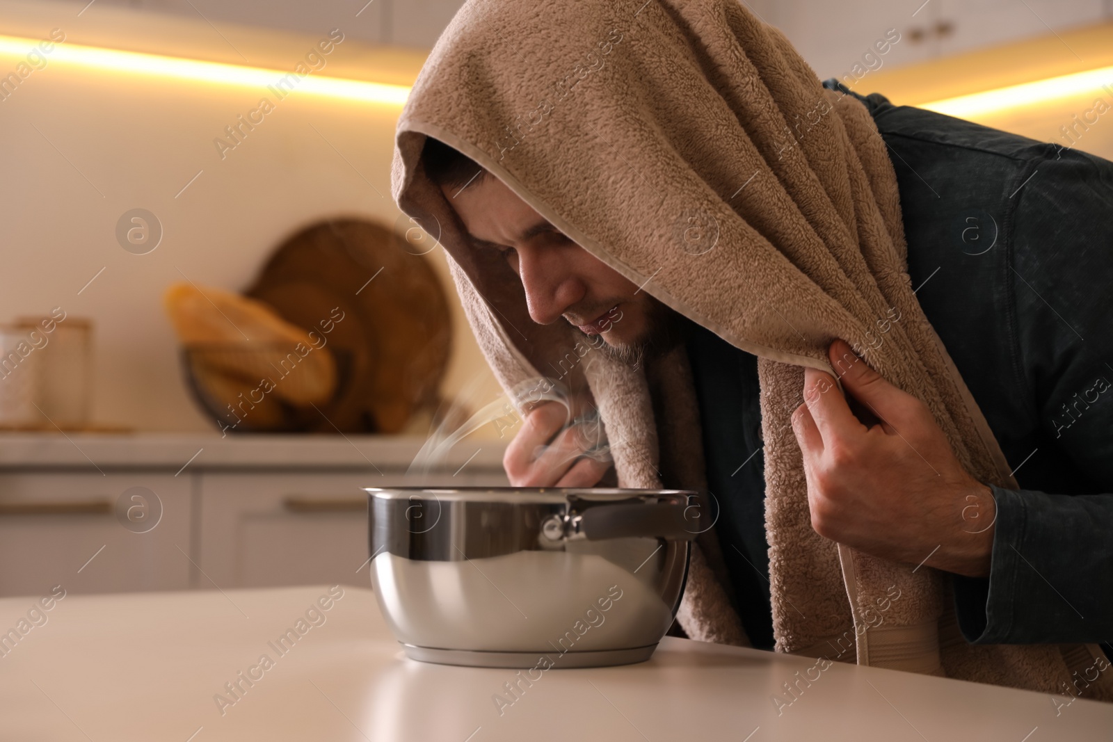 Photo of Man taking treatments at table indoors. Steam inhalation