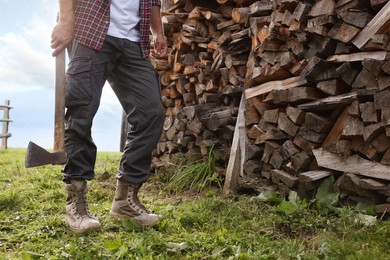 Photo of Man with ax near log pile outdoors, closeup