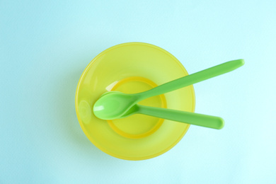 Small bowl and spoons on light blue background, top view. Serving baby food