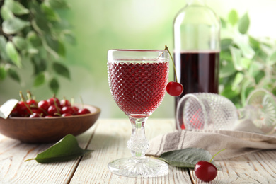 Photo of Delicious cherry wine with ripe juicy berries on white wooden table
