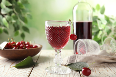 Delicious cherry wine with ripe juicy berries on white wooden table