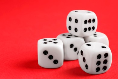 Photo of Many white game dices on red background, closeup