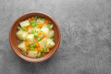 Photo of Bowl of fresh homemade vegetable soup on grey background, top view. Space for text