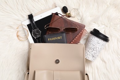 Photo of Stylish urban backpack and different items on white faux fur, flat lay