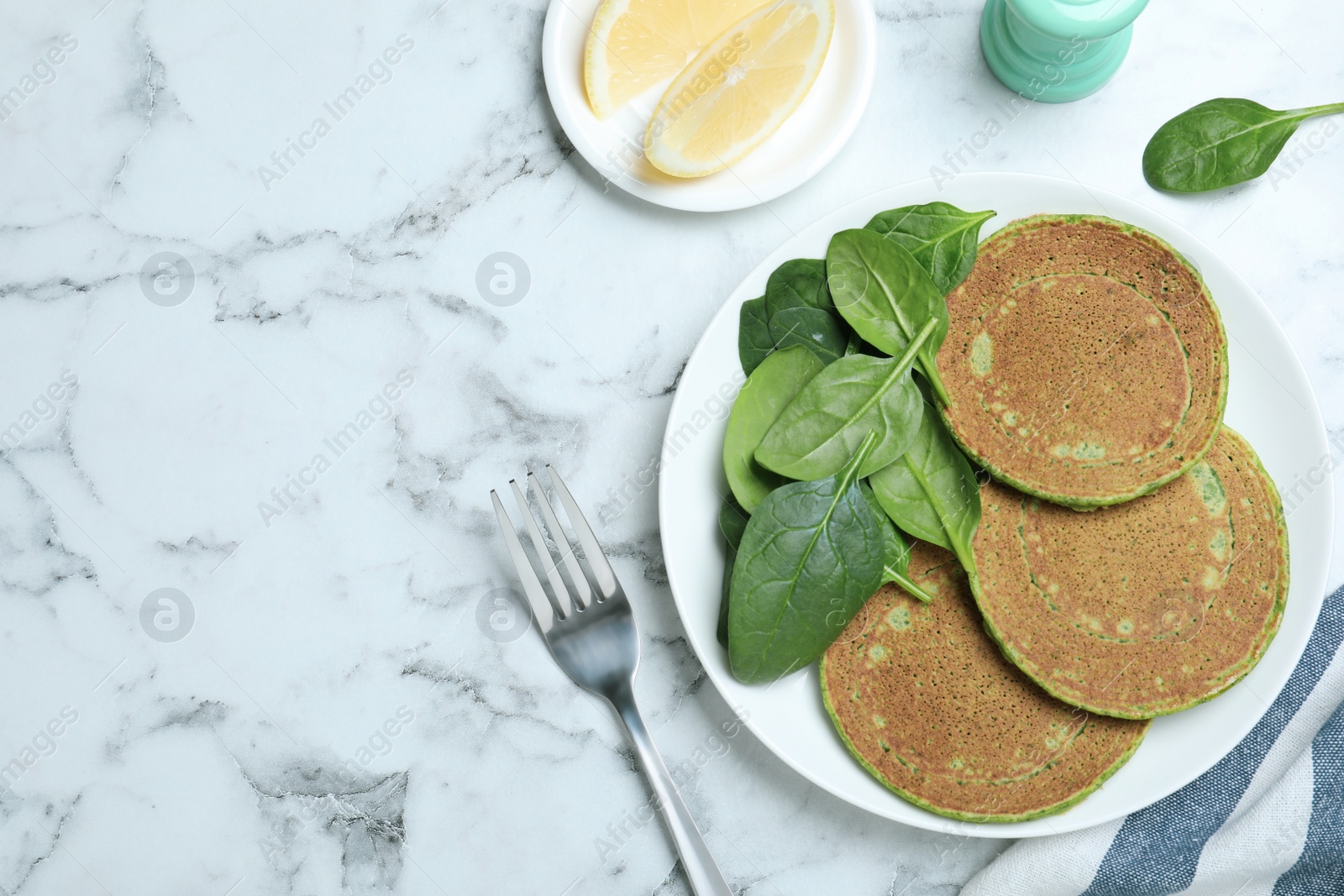 Photo of Tasty spinach pancakes served on white marble marble table, flat lay. Space for text