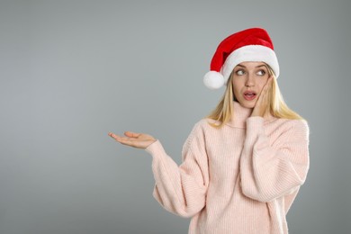 Photo of Woman in Santa hat on grey background, space for text. Christmas countdown
