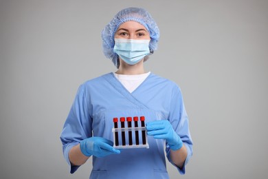 Photo of Laboratory testing. Doctor with blood samples in tubes on light grey background