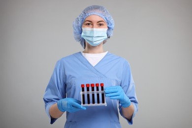 Laboratory testing. Doctor with blood samples in tubes on light grey background