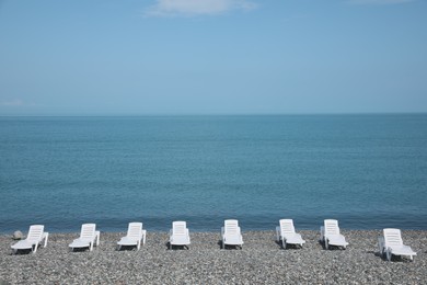 Photo of Beautiful view of sunbeds on pebble beach near sea