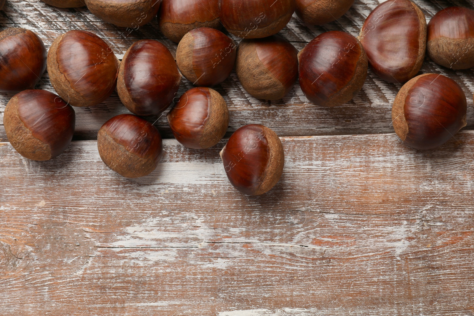 Photo of Sweet fresh edible chestnuts on wooden table, top view. Space for text