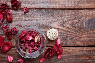 Aromatic potpourri of dried flowers in glass jar on wooden table, flat lay. Space for text