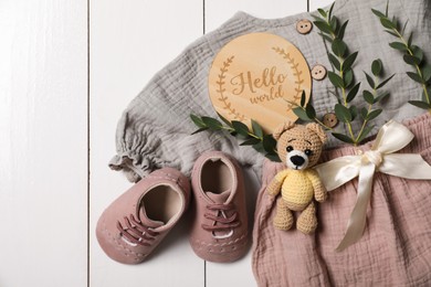 Photo of Flat lay composition with children's clothes, shoes and toy on white wooden table