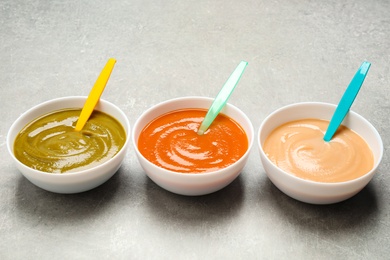 Healthy baby food in bowls on grey table