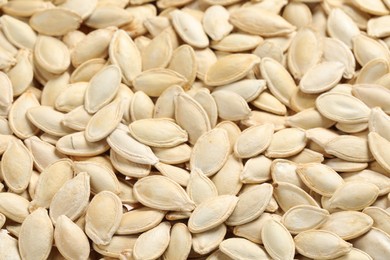 Photo of Many pumpkin seeds as background, closeup view