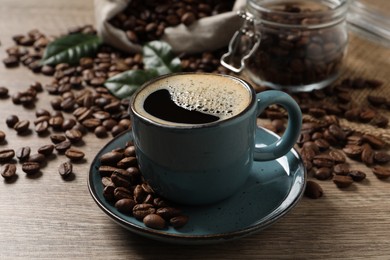 Photo of Cup of aromatic hot coffee and beans on wooden table