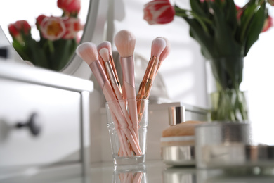 Different cosmetic brushes on dressing table indoors. Interior element