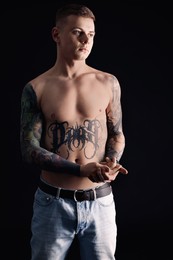 Photo of Shirtless young man with tattoos on black background