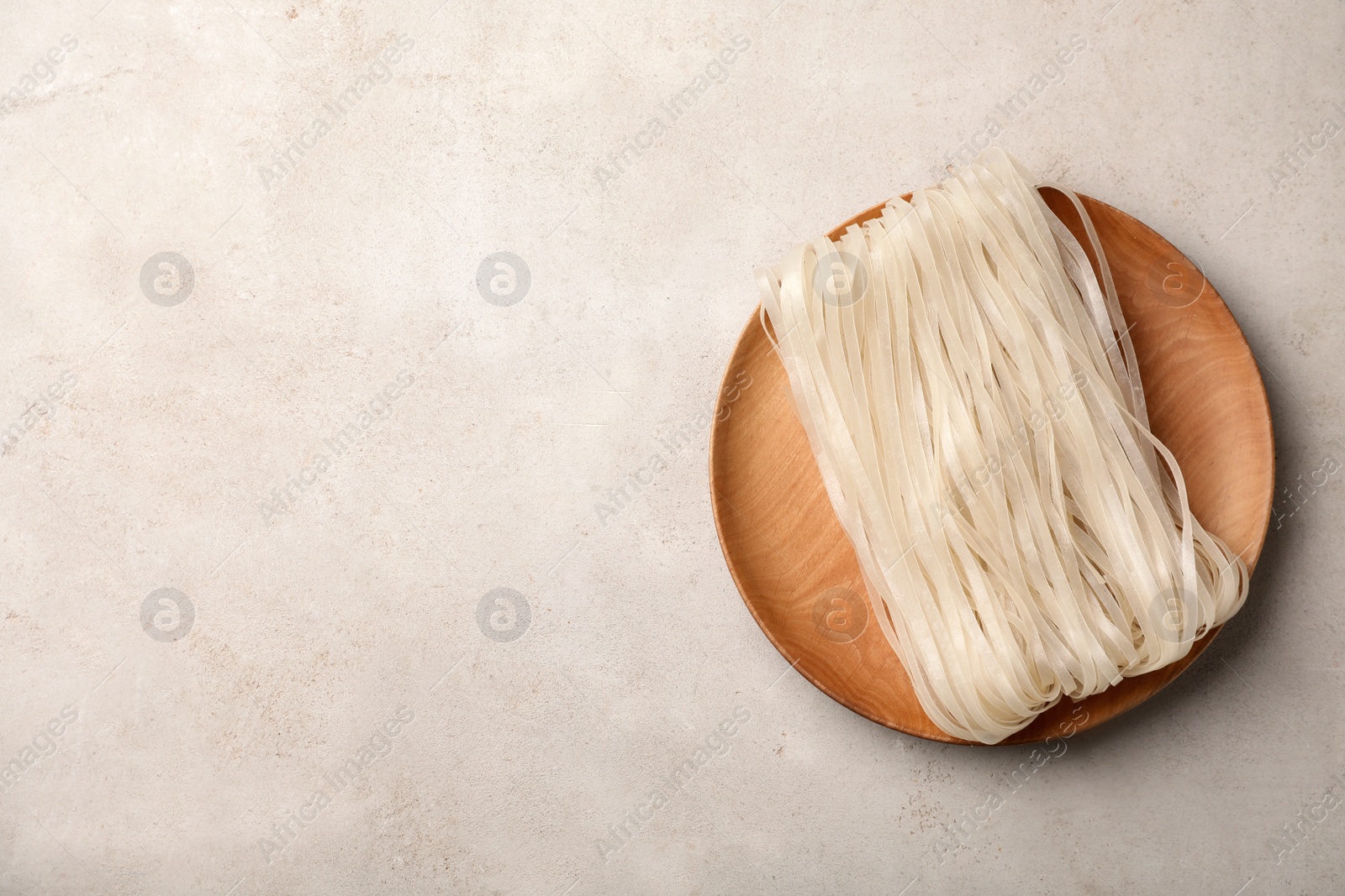 Photo of Plate with raw rice noodles on grey background, top view. Space for text