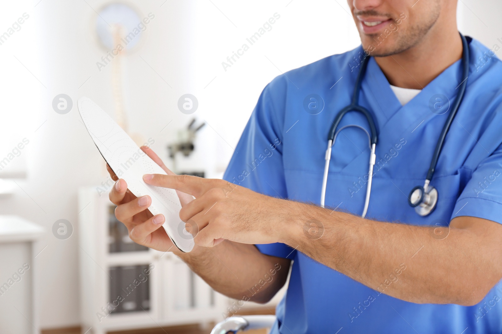 Photo of Male orthopedist showing insole in clinic, closeup