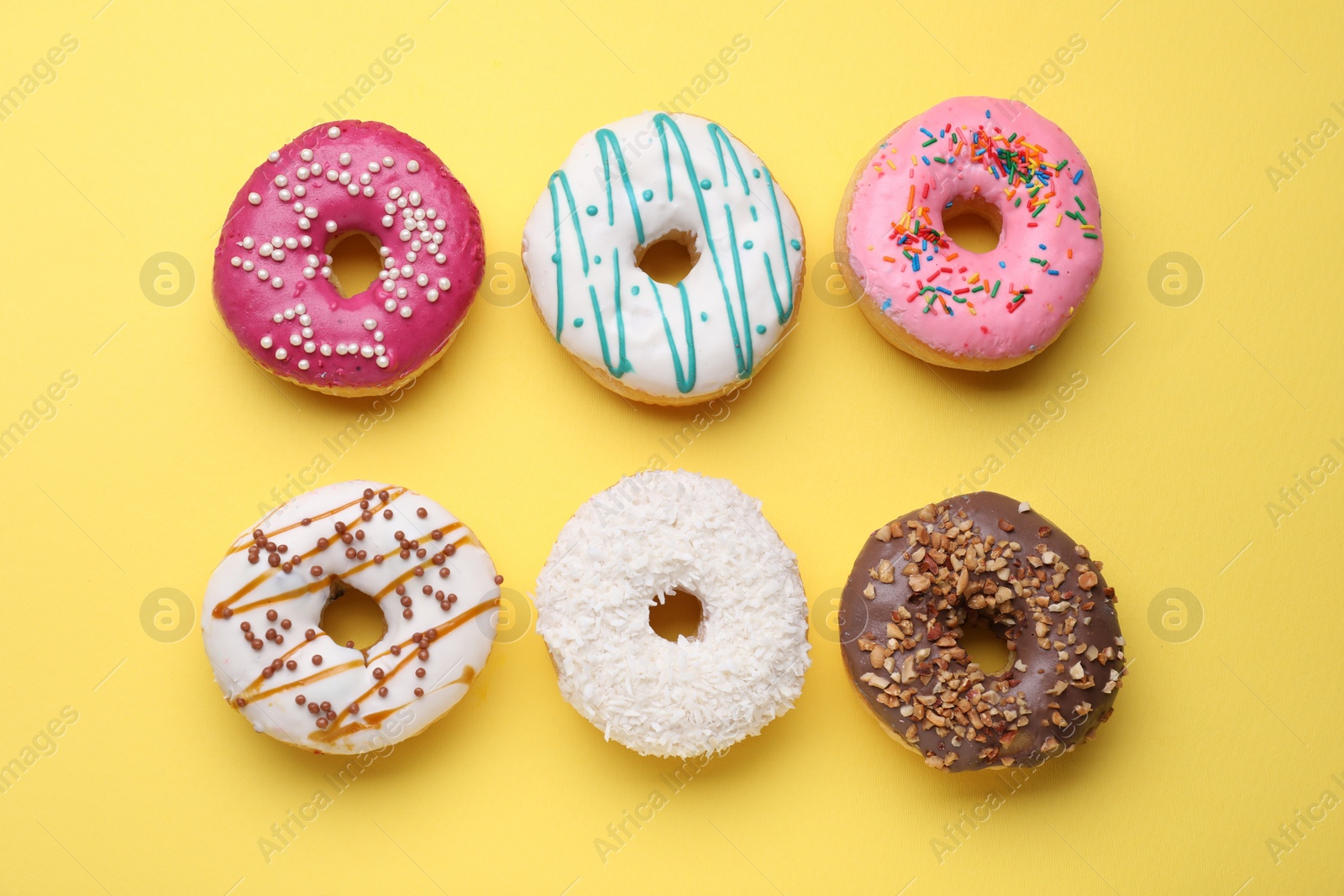Photo of Tasty glazed donuts on yellow background, flat lay