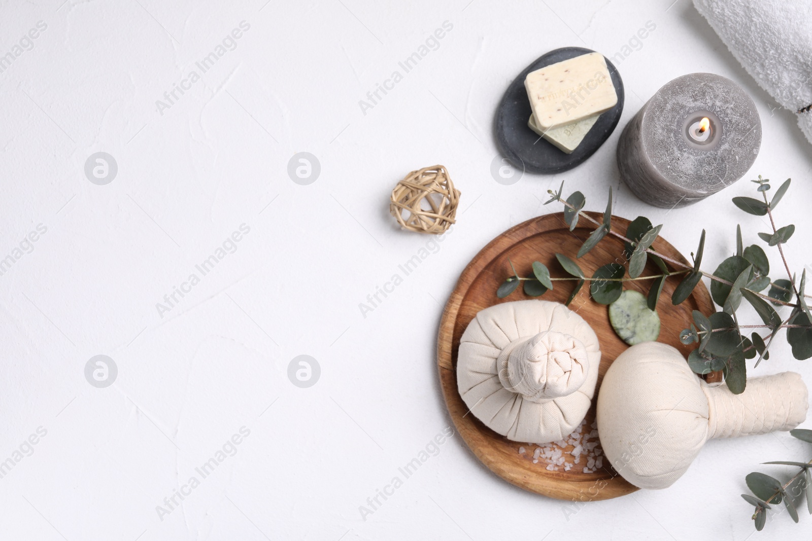 Photo of Flat lay composition with herbal massage bags, spa products and eucalyptus branches on white table. Space for text