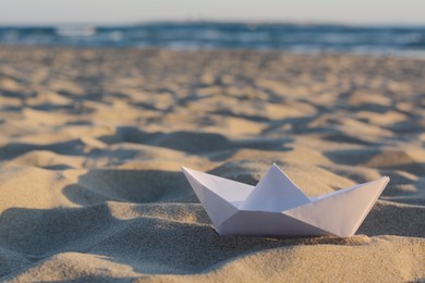 Beautiful white paper boat on sand outdoors, space for text
