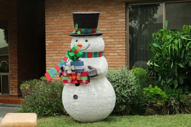 Funny snowman near house outdoors. Festive Christmas decoration