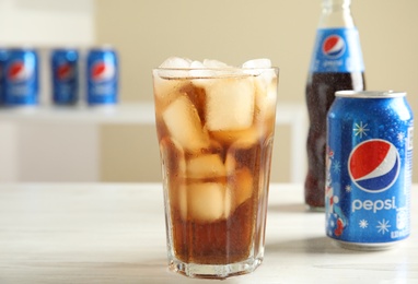 Photo of MYKOLAIV, UKRAINE - FEBRUARY 10, 2021: Glass, can and bottle of Pepsi on white wooden table