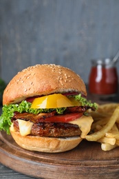 Photo of Fresh juicy bacon burger on wooden board against grey background