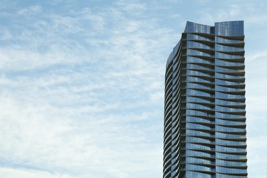 Photo of Exterior of modern skyscraper against cloudy sky, space for text