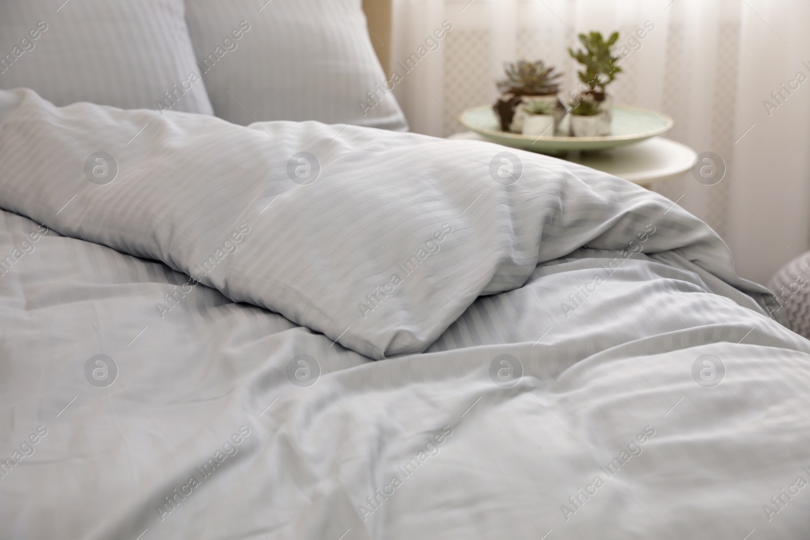 Photo of Comfortable bed with soft blanket indoors, closeup