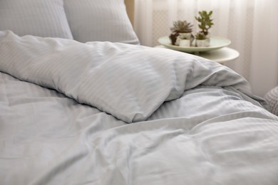 Photo of Comfortable bed with soft blanket indoors, closeup