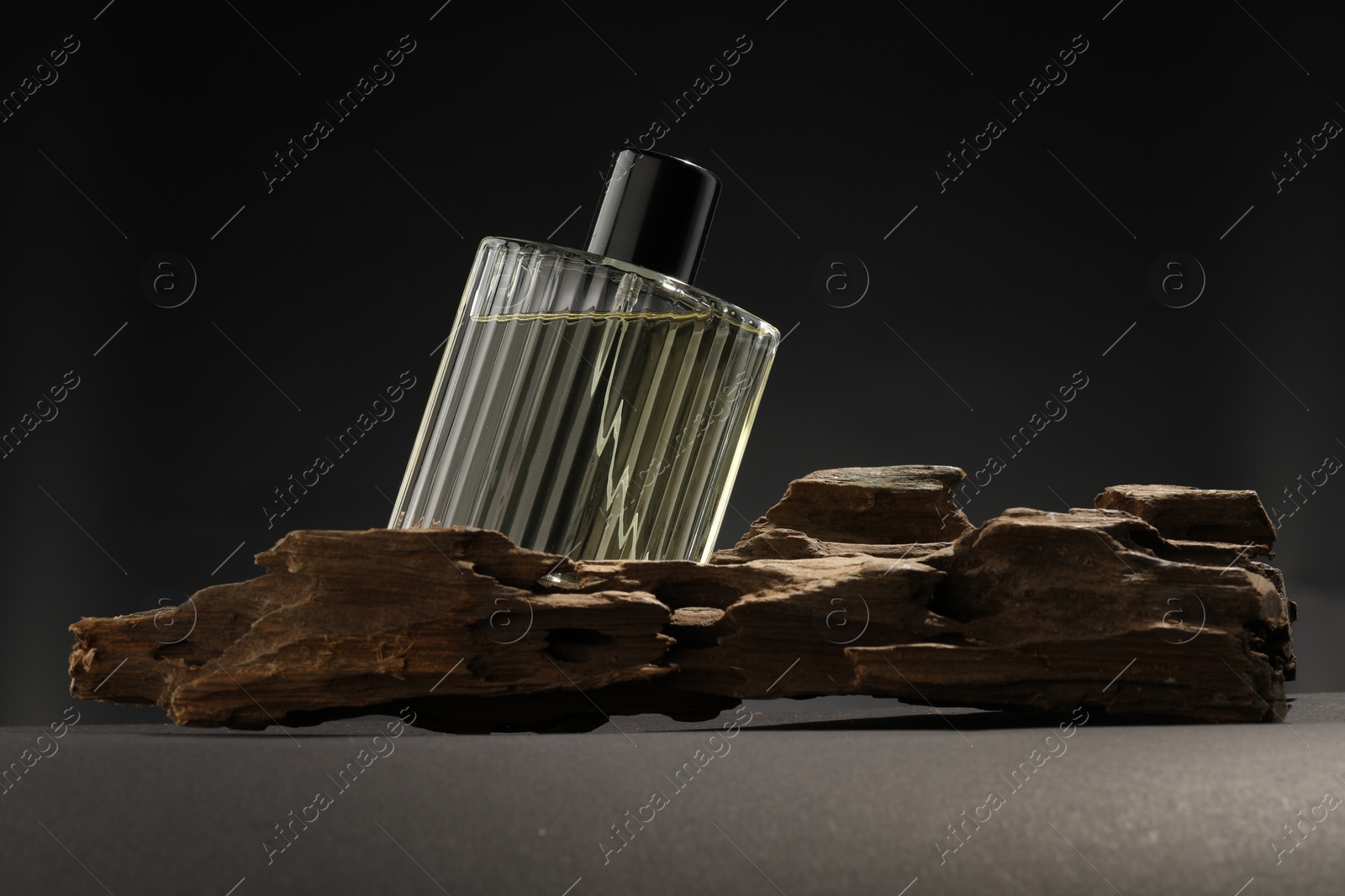 Photo of Luxury men`s perfume in bottle on grey table against dark background