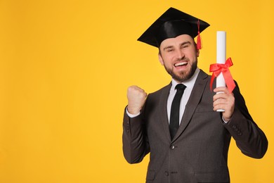 Photo of Emotional student with graduation hat and diploma on yellow background. Space for text