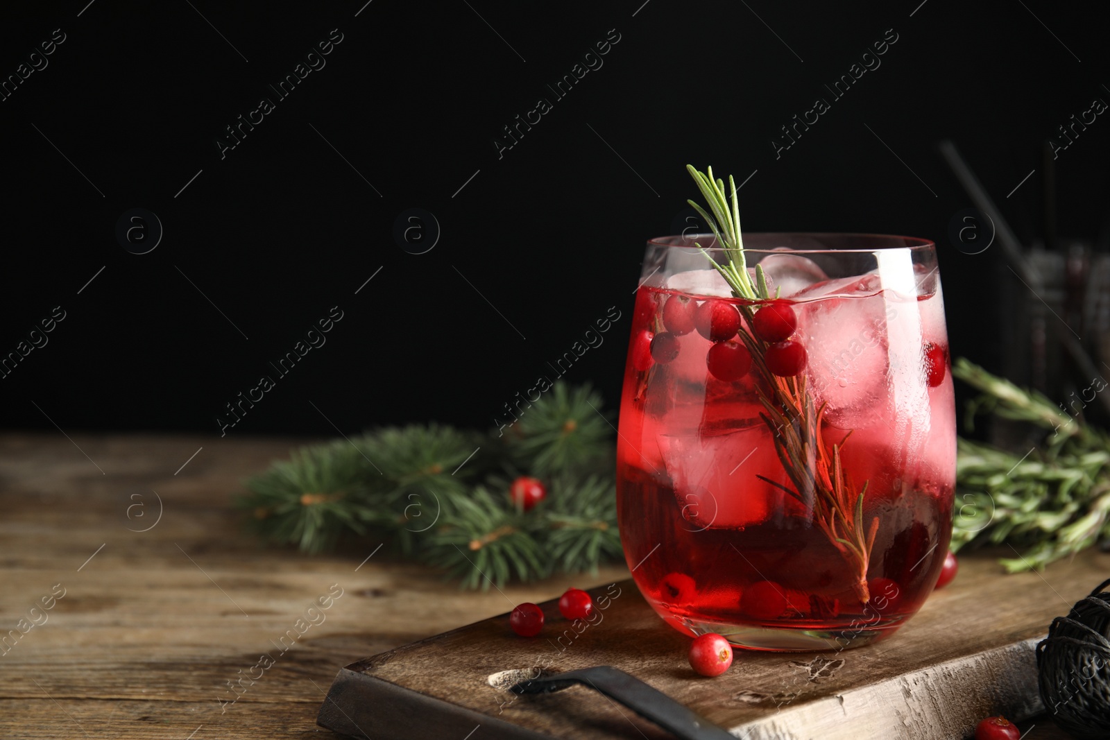 Photo of Tasty refreshing cranberry cocktail with rosemary on wooden table. Space for text