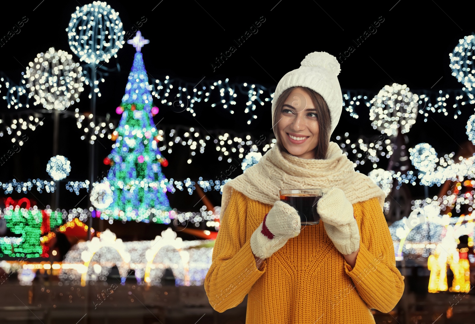 Image of Happy beautiful woman with cup of mulled wine at Christmas fair