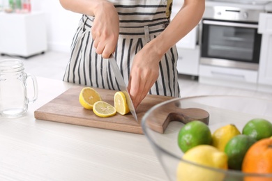 Photo of Young woman preparing lemonade on table, closeup. Natural detox drink