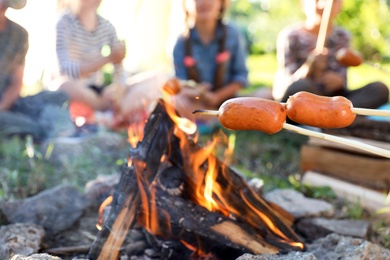 Photo of Frying sausages on bonfire, closeup. Summer camp