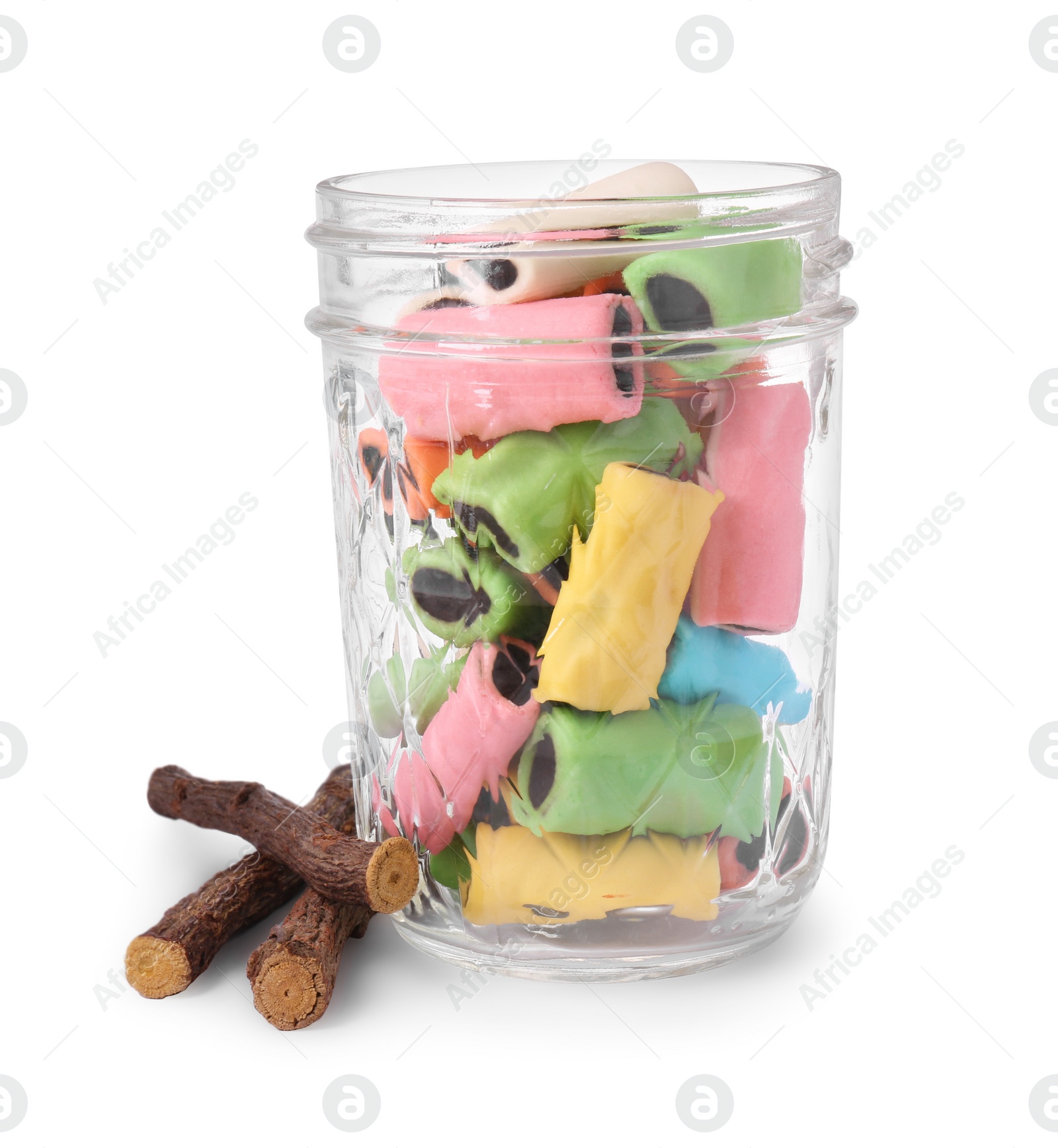 Photo of Glass jar of tasty candies and dried cut liquorice root isolated on white