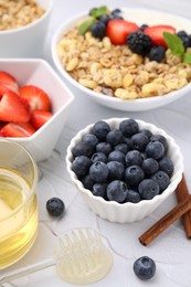 Photo of Fresh berries, oatmeal and honey on white textured table, closeup. Healthy breakfast