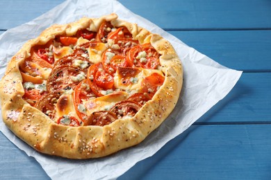 Tasty galette with tomato and cheese (Caprese galette) on blue wooden table, closeup