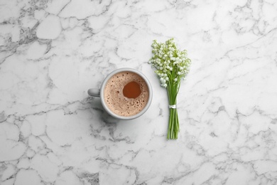 Lily of the valley bouquet and coffee on marble background, flat lay