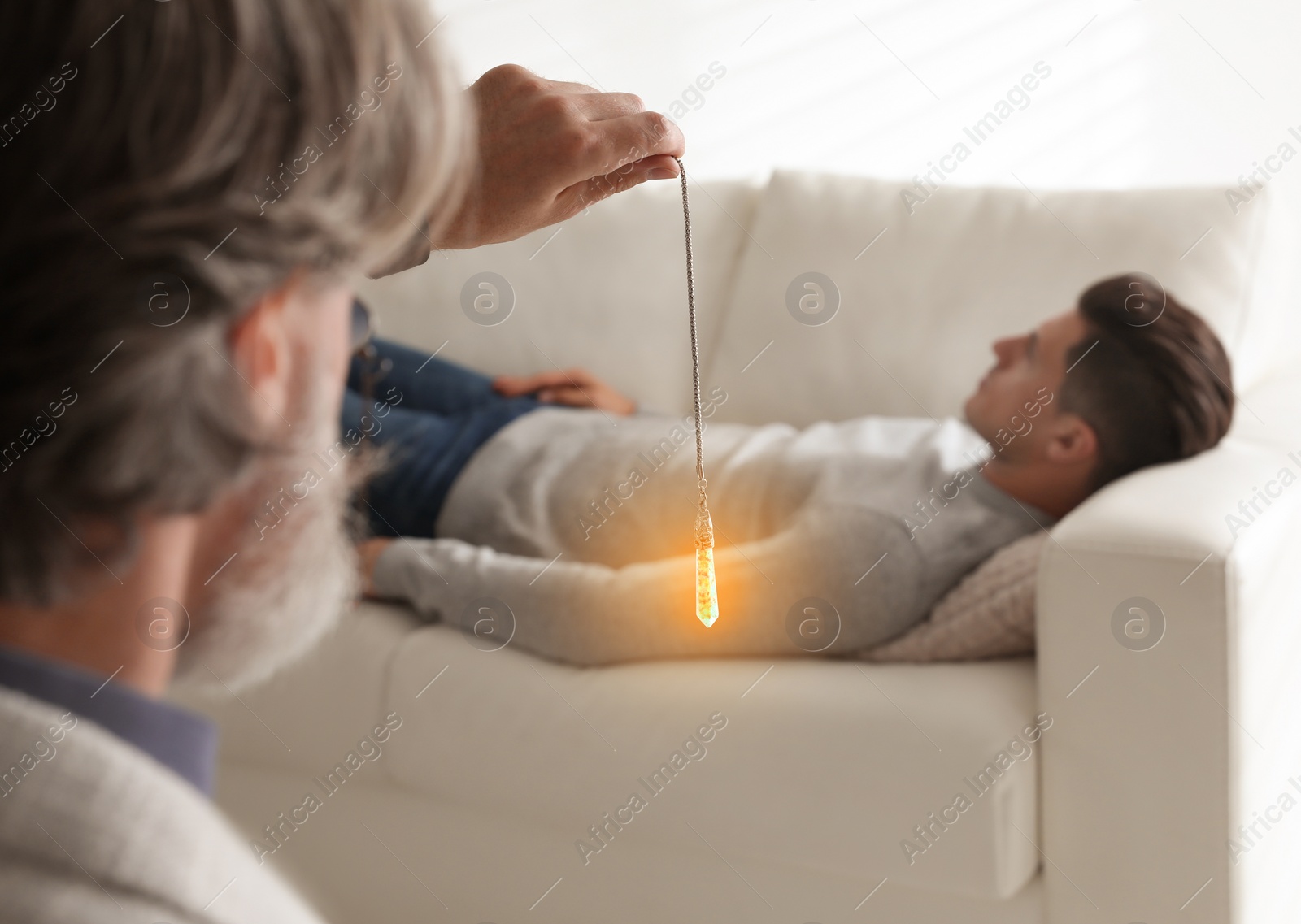 Photo of Psychotherapist using pendulum during hypnotherapy   session in office