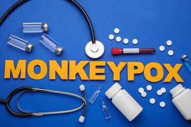 Photo of Flat lay composition with word Monkeypox and medical supplies on blue background