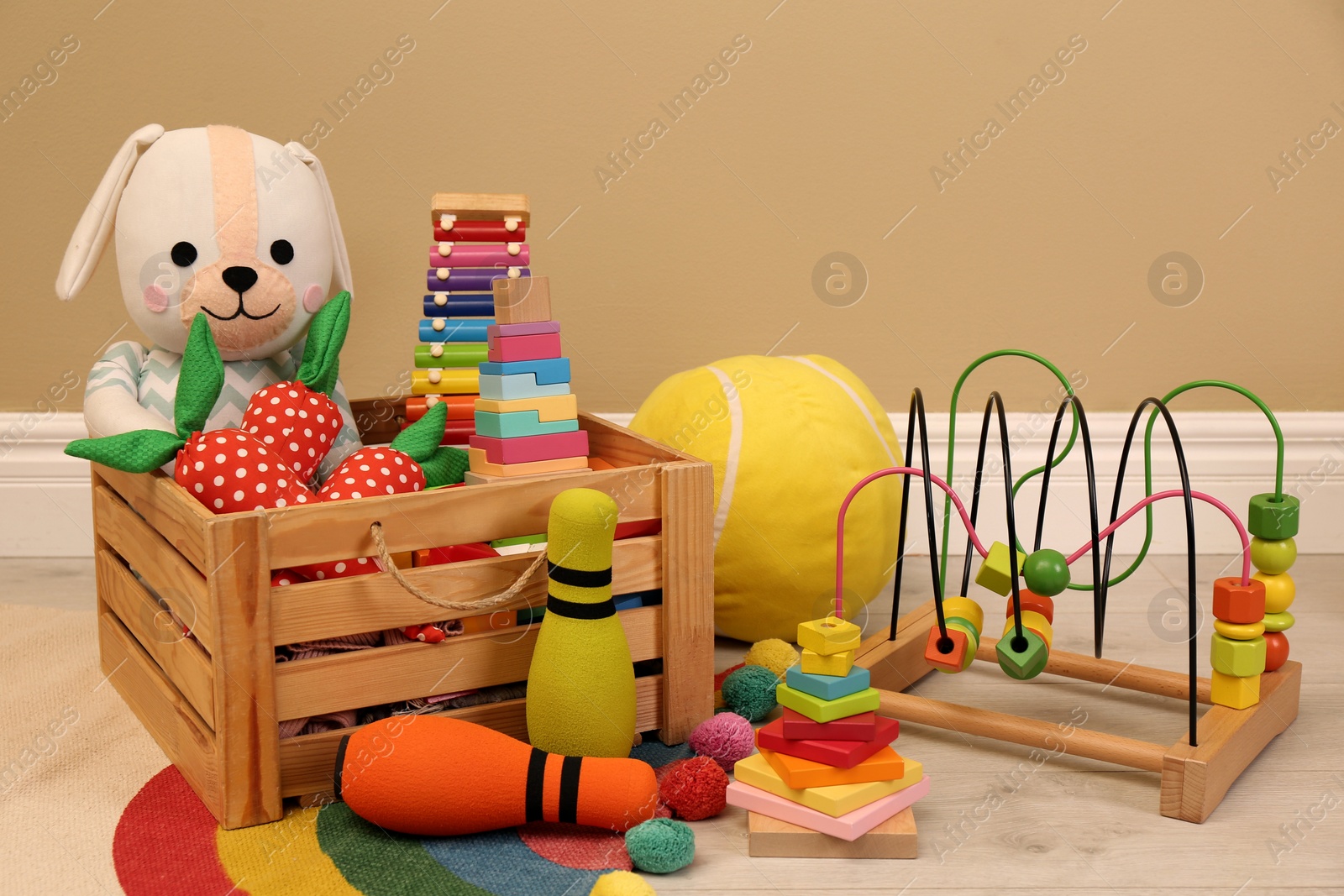 Photo of Set of different cute toys on floor near beige wall