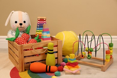 Set of different cute toys on floor near beige wall